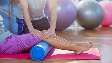 Physical therapist helping a patient with legs up on a roller